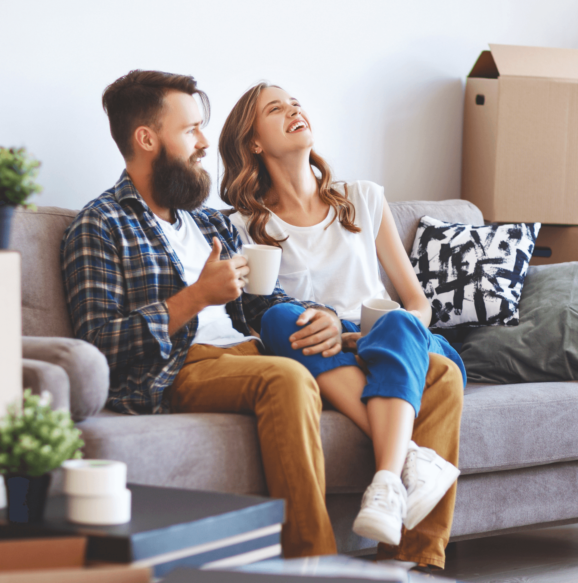 Dos personas sentadas en un sillón, con un tazón de café en la mano y sonriendo.