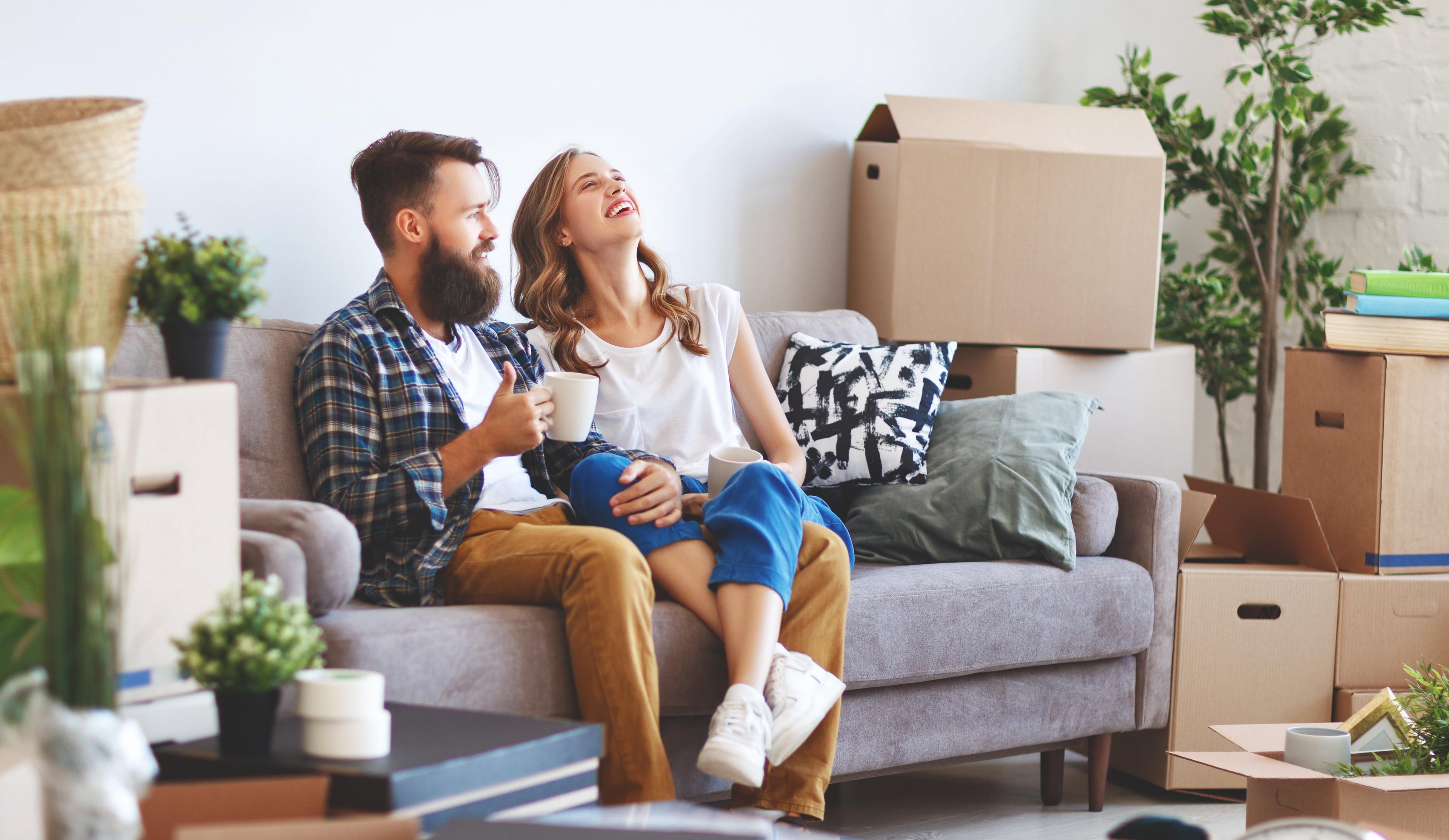 Dos personas sentadas en un sillón, con un tazón de café en la mano y sonriendo.