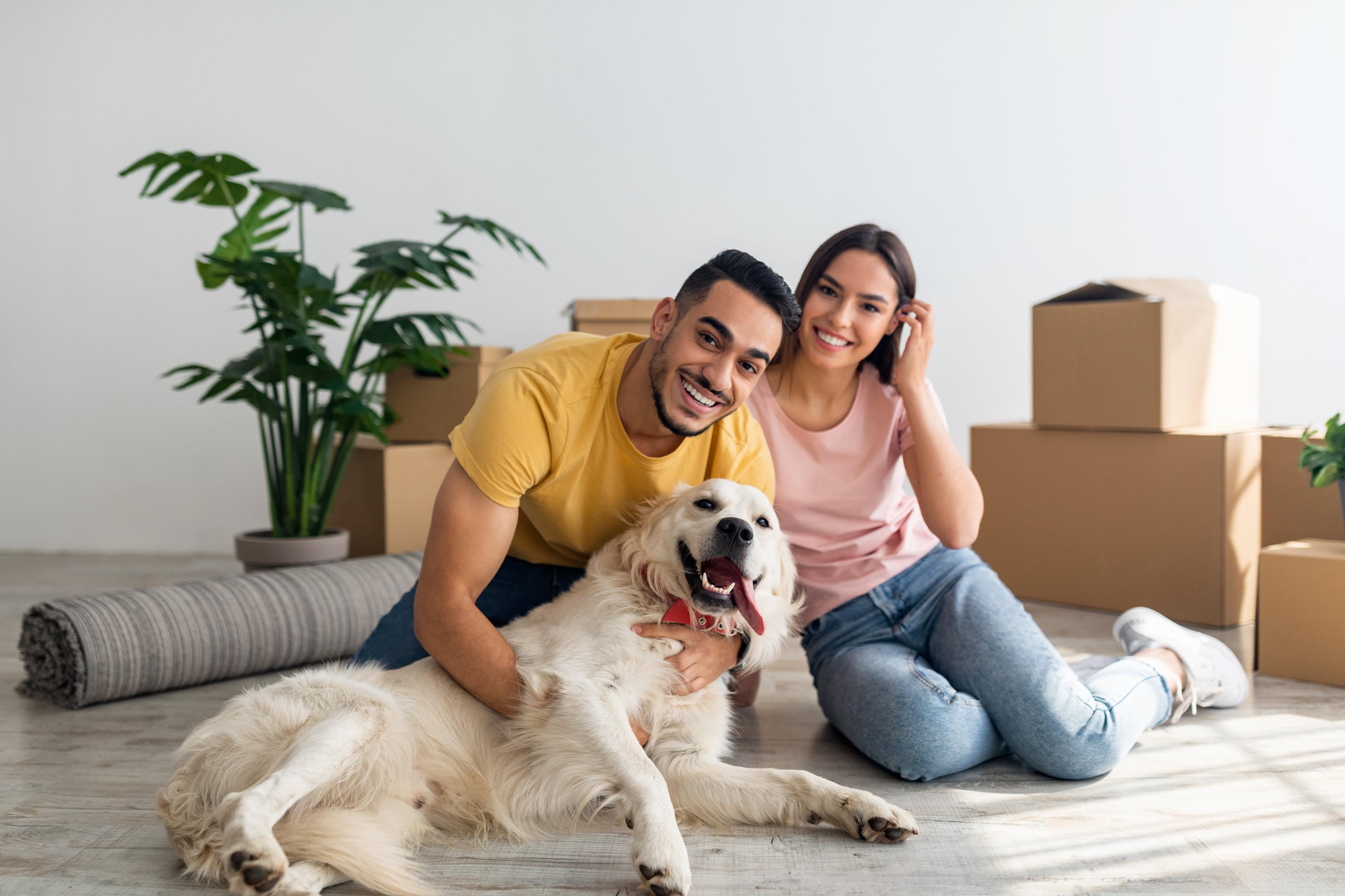 Dos personas sentadas, sonriendo con un perro en sus manos.