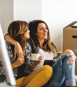 Mujeres sonriendo mudándose al arrendar su hogar soñado.